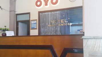 Un comptoir d’accueil avec une enseigne indiquant « OYO HOTEL MEGA SENTOZA ».