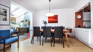 Eine moderne Küche mit Essbereich, mit einem Holztisch, schwarzen Stühlen und einer roten Akzentwand.