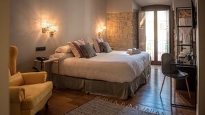 A bedroom with a large bed, bedside tables, a chair, and a wardrobe. - Hotel Don Juan Boutique (Úbeda)