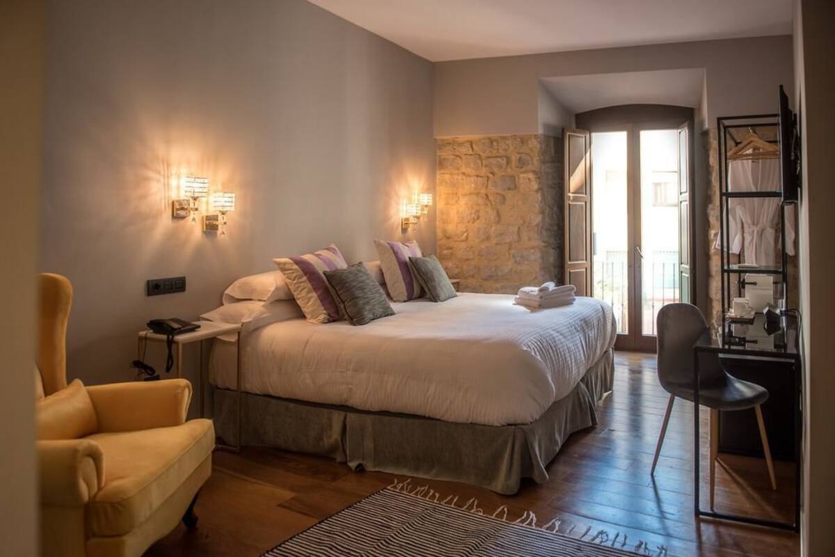 Un dormitorio con una cama grande, mesitas de noche, una silla y un armario.