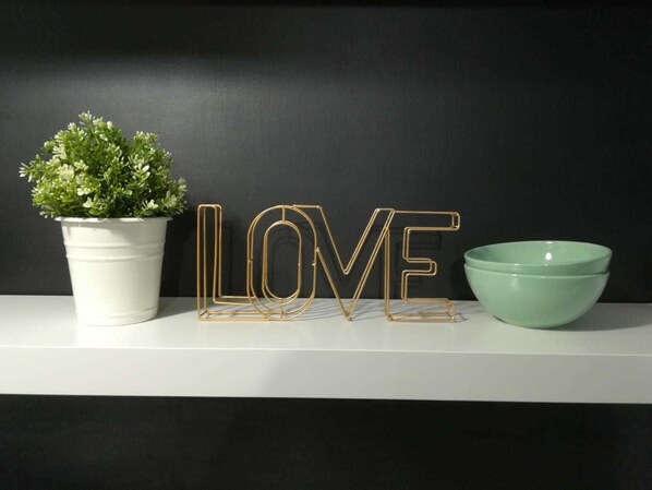 A white shelf with a potted plant, a green bowl, and a gold-lettered 'LOVE' sign against a dark background. - B&B Piccolo Loft del Borgo (Lanciano)