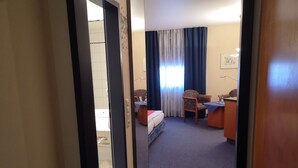 A hotel room with a bed, a desk, a chair, and a window with curtains. - Main Hotel Eckert (Margetshoechheim)
