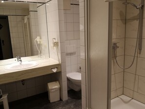 A bathroom with a sink, mirror, toilet, and shower. - Main Hotel Eckert (Margetshoechheim)