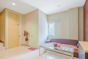 Una sala de estar con un sofá, una mesa de centro, una puerta y una ventana.
