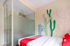A hotel room with a bed, a glass shower enclosure, and a wall with colorful abstract art. - Capital O 1121 Orienchi 2 (Jakarta)