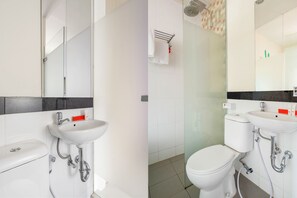 A modern bathroom with a white sink, toilet, and glass shower enclosure. - Capital O 1121 Orienchi 2 (Jakarta)