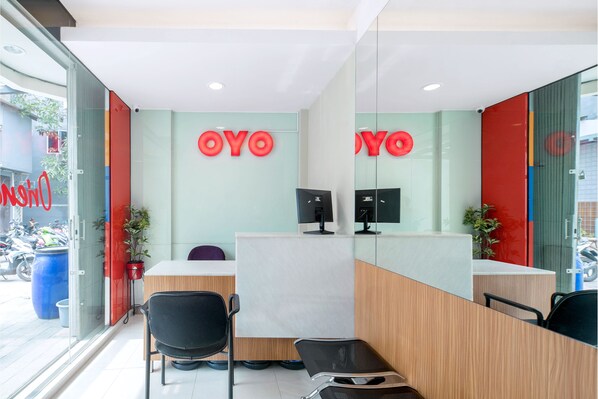 A reception area with a wooden desk, two black chairs, and a computer monitor. - Capital O 1121 Orienchi 2 (Jakarta)