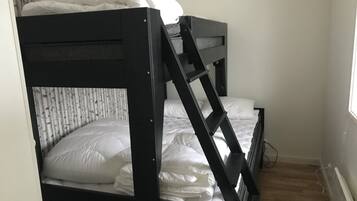 A bunk bed with a ladder, white bedding, and a wooden floor.