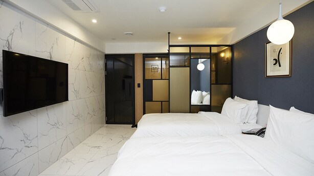 A modern hotel room with a large bed, a flat-screen TV mounted on the wall, and a separate entrance door. - Hotel No25 Songdo (Incheon)