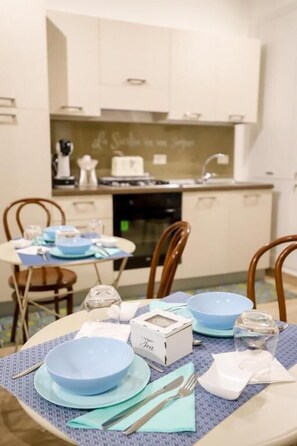 A dining area with a table set for four, featuring blue plates and a white box labeled "Tea". - La Sicilia in un sogno (Syracuse)