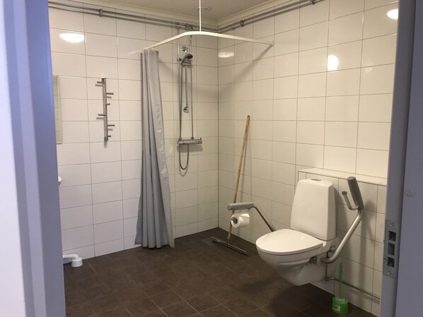 A modern bathroom with a shower, toilet, and handrail. - Åsens Vandrarhem Uvboet - Hostel (Alvdalen)