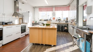 Een moderne keuken met witte kasten, een centraal eiland en een groot raam met rode gordijnen.