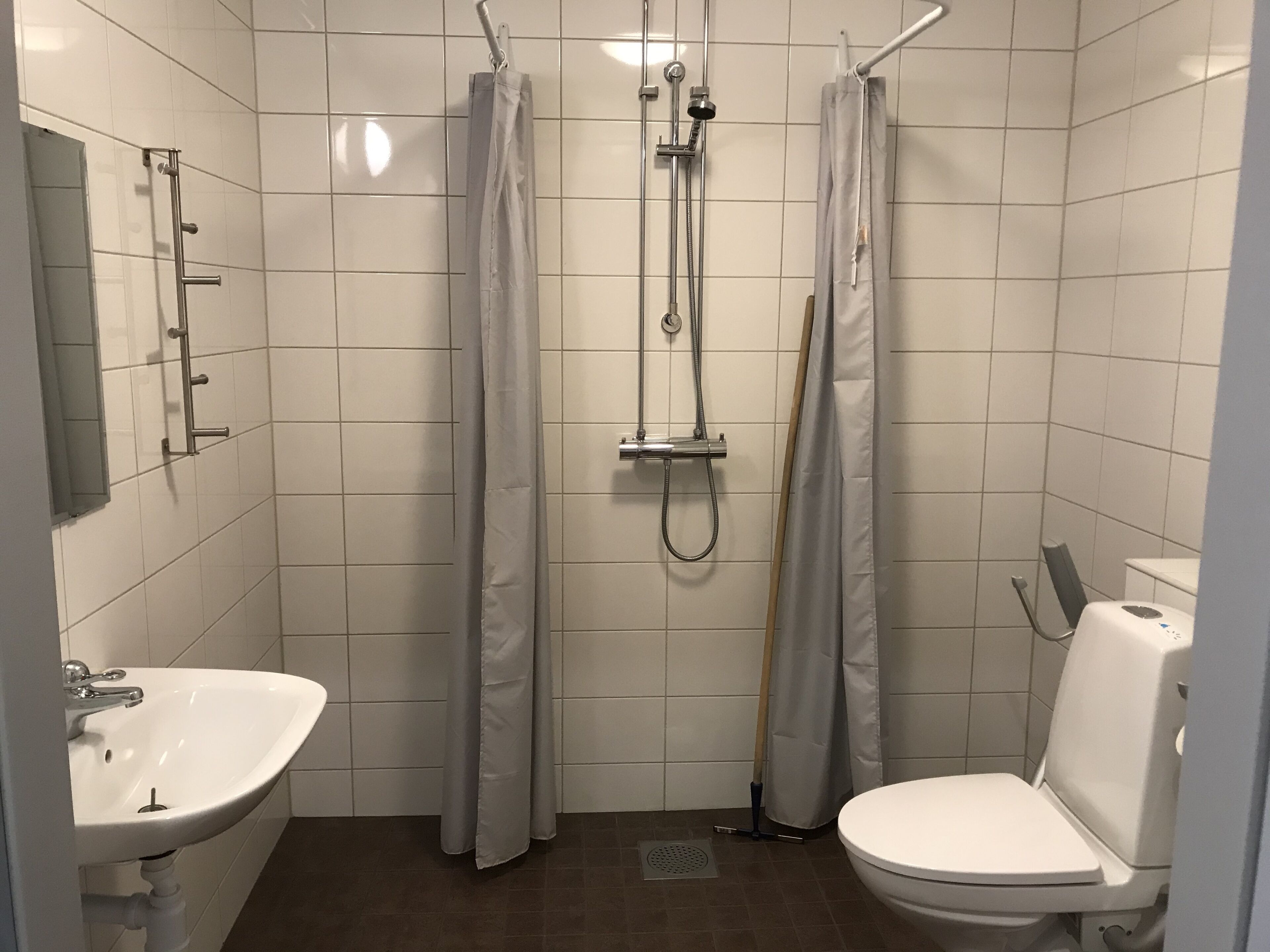 A small, tiled bathroom with a sink, toilet, and shower.