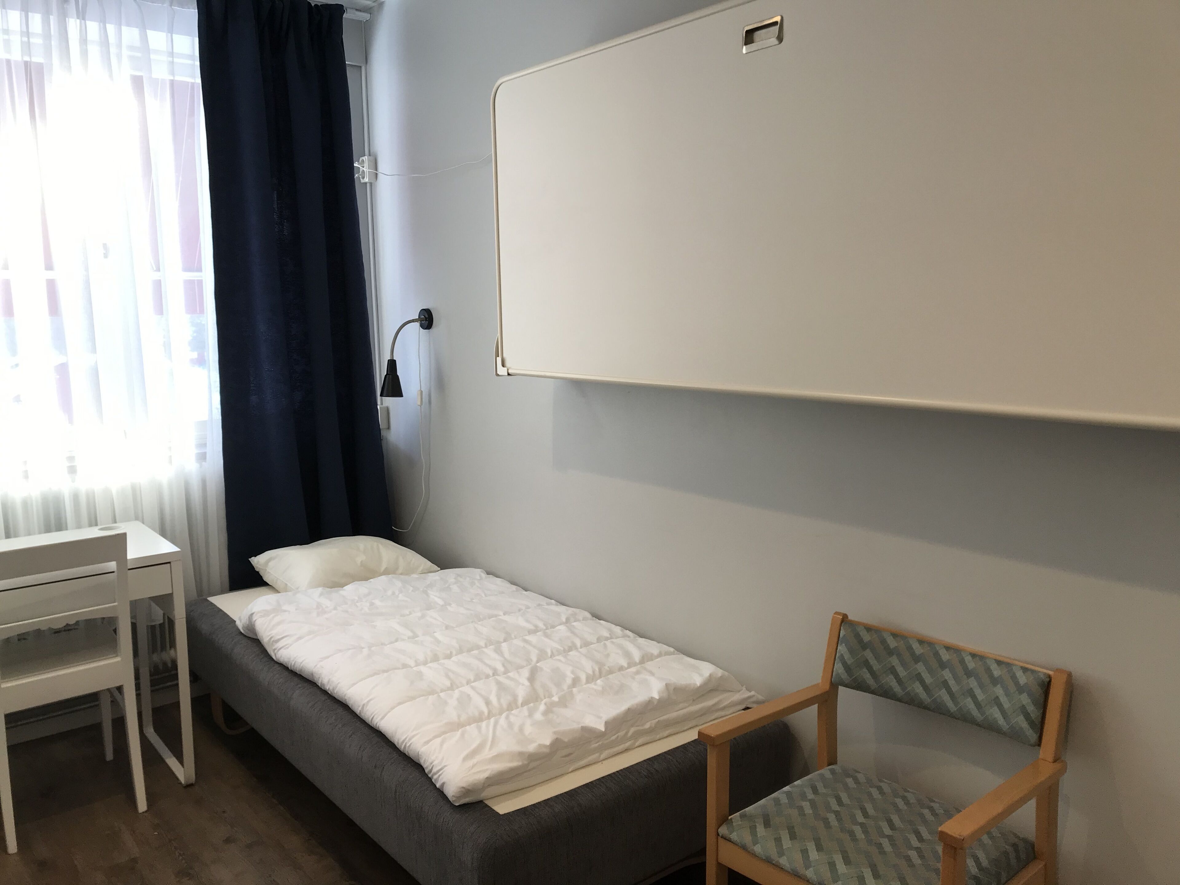 Una camera da letto piccola e ordinata, con un letto, una scrivania e una sedia.