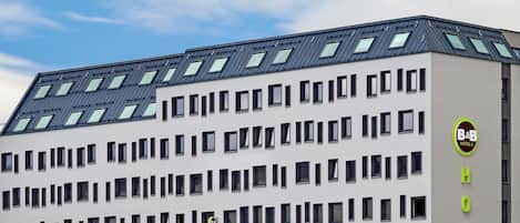 En modern hotellbyggnad med ett platt tak, många fönster och en skylt som visar att det är ett hotell av typen bed and breakfast.