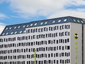 Un hôtel moderne, avec un toit plat, de nombreuses fenêtres et une enseigne indiquant qu’il s’agit d’un hôtel proposant également un service de chambre et de petit-déjeuner.