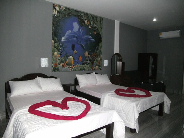 Une chambre d’hôtel avec deux lits, chacun agrémenté d’un motif en forme de cœur sur la couverture.