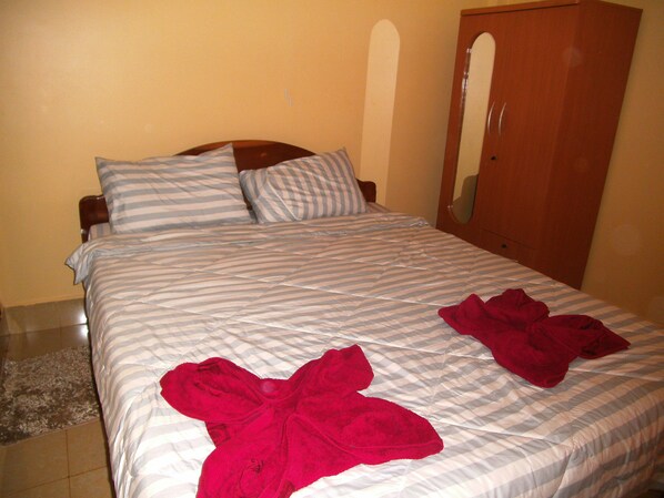 A bed with striped bedding and two red towels on it. - Sun Boutique Resort (Siem Reap)