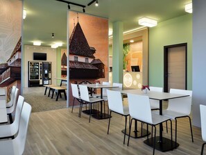 Un moderno vestíbulo de hotel con un área de estar central, una máquina expendedora y un mostrador de recepción.