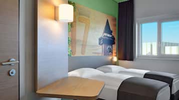 Habitación de hotel con dos camas, una mesita, una lámpara de pared y ventana con vistas a edificios.