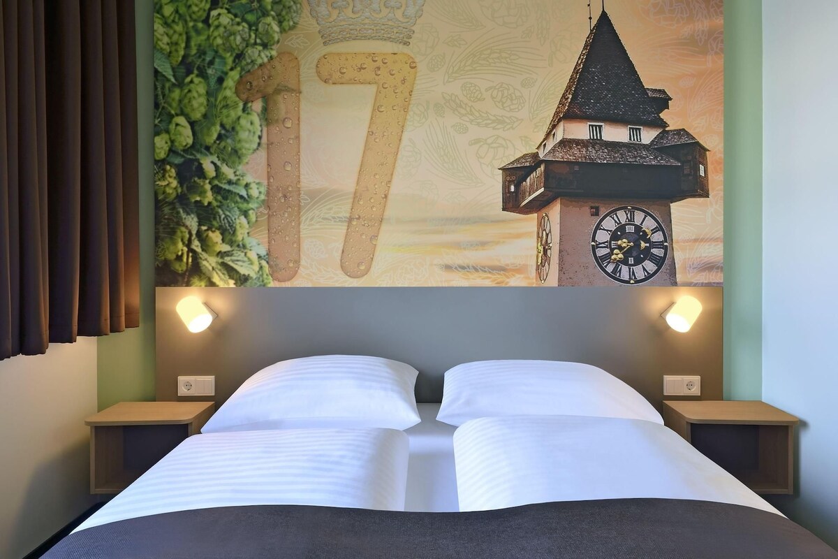 Ein Hotelzimmer mit einem Bett, zwei Nachttischen, einer Wanduhr und einem großen Wandbild mit der Zahl 17.