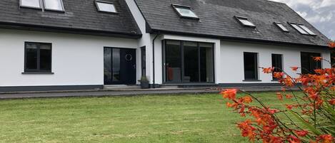 A modern house with a sloped roof, large windows, and a well-maintained lawn.