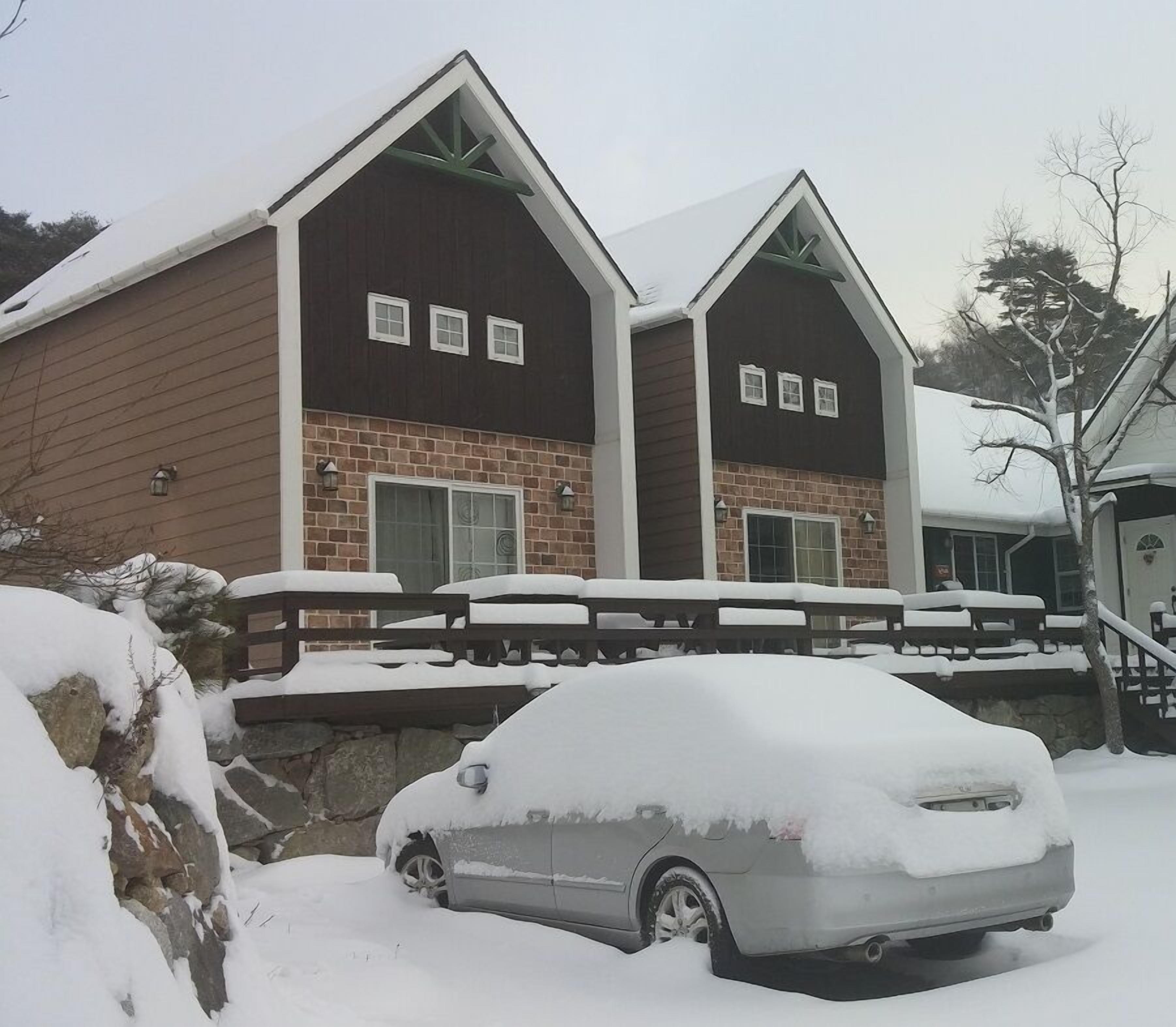 A two-story house with a brick facade and a wooden deck.