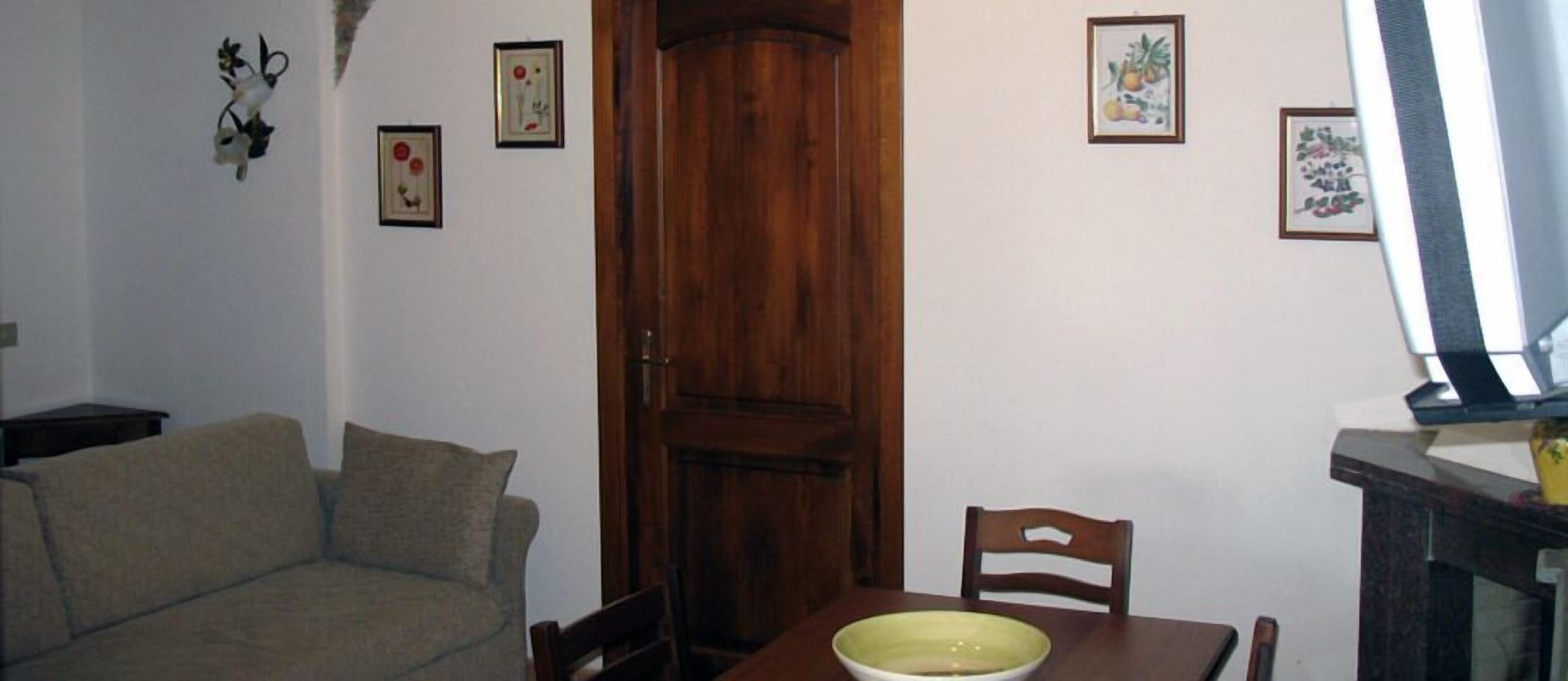 Ein Wohnzimmer mit einer Couch, einem Esstisch mit einer Schüssel und einer Holztür.