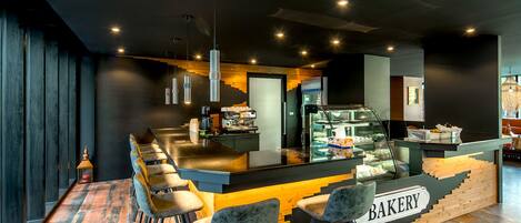 A bakery counter with a sign, bar stools, and a display case.