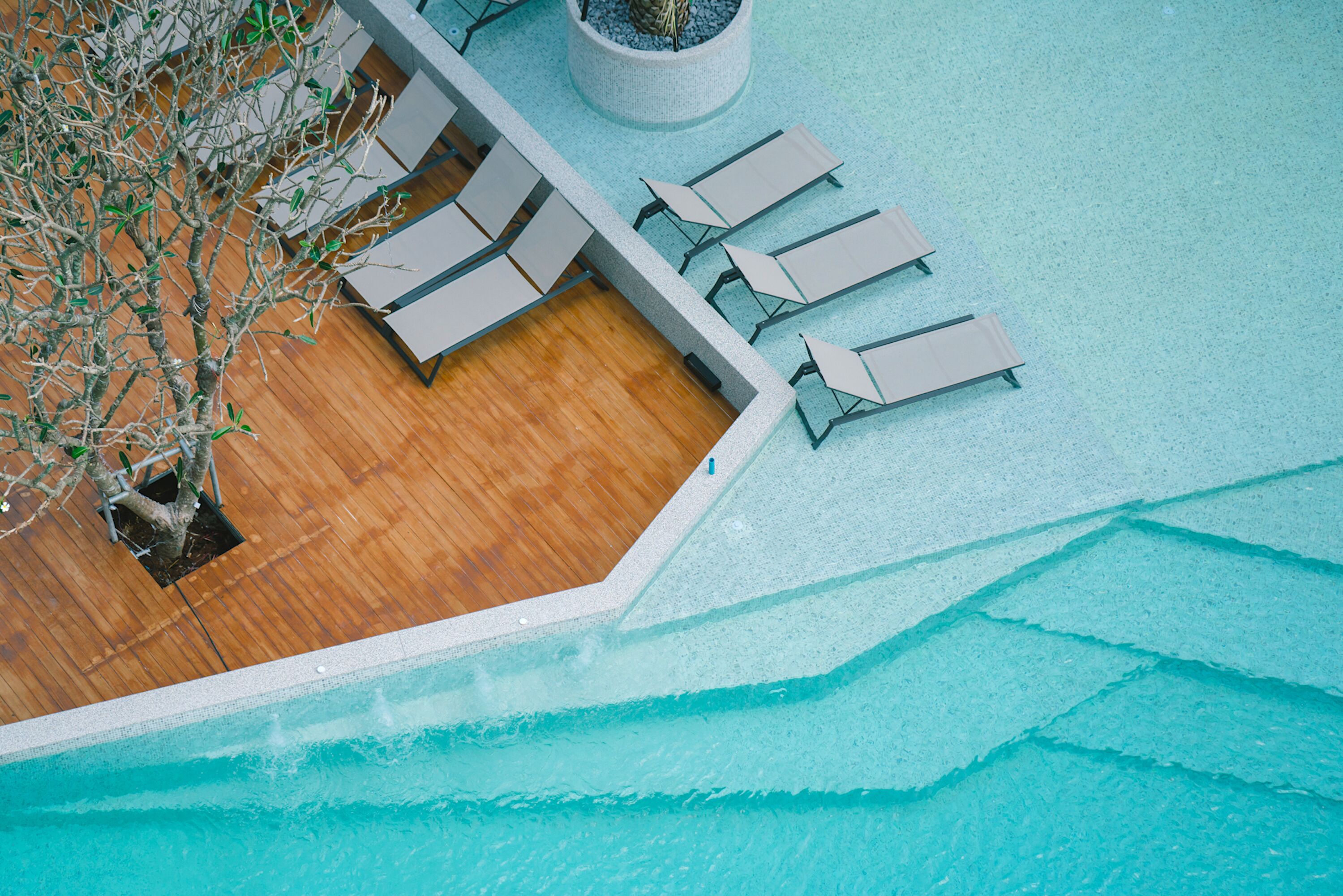 Eine Vogelperspektive auf einen Poolbereich mit Liegestühlen und einer Holzterrasse.