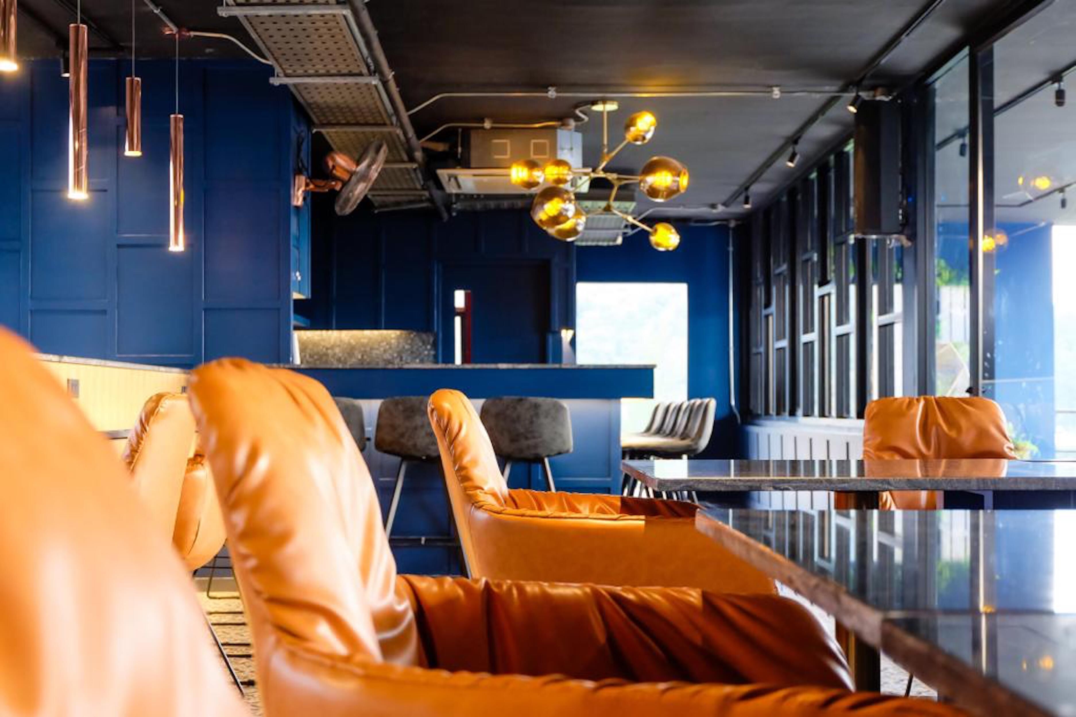 A modern interior with leather seating, a glass table, and pendant lighting.