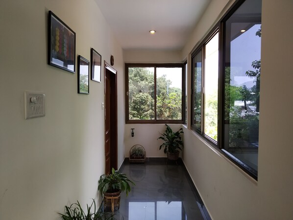 A hallway with a large window, a door, and several potted plants. - Hotel Centre Point Tezpur (Tezpur)