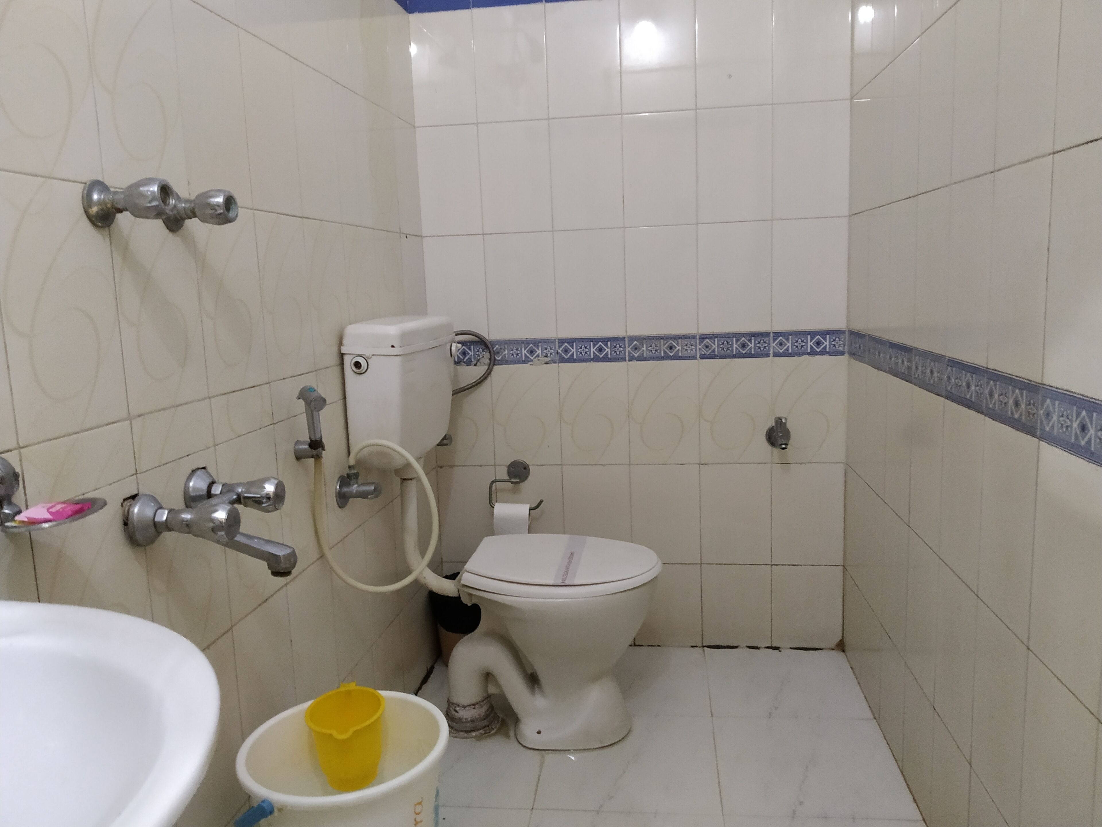 A small bathroom with a toilet, sink, and a yellow bucket.