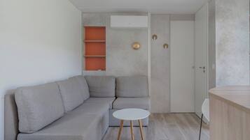 A modern living room with a grey sectional sofa, a small white round table, and a wooden side table.