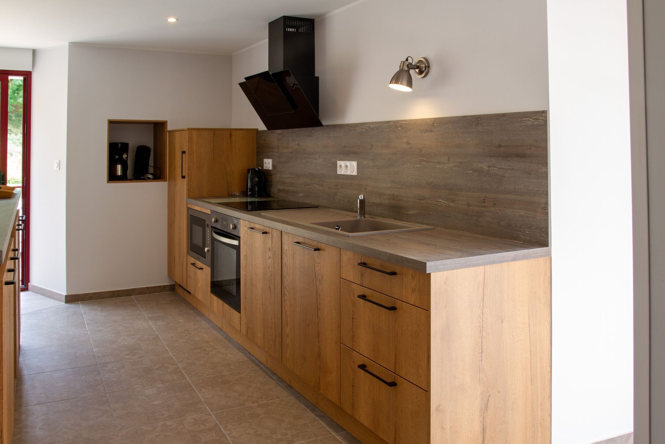 Una cucina moderna con mobili in legno, un lavello in acciaio inossidabile e un forno integrato.