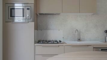 A modern kitchen with a built-in microwave, gas stove, and stainless steel sink.