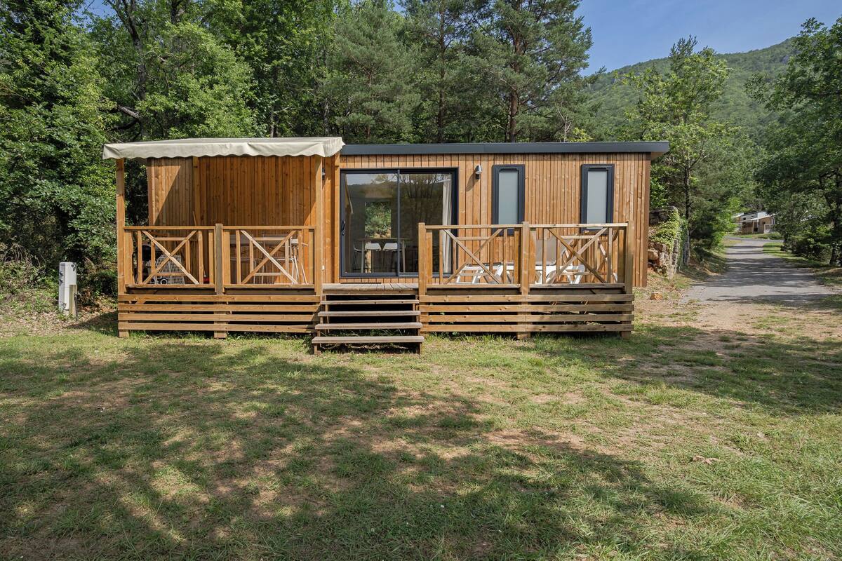 Una baita in legno con una veranda, ampie finestre e una porta.