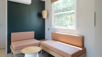 A modern room with a sectional sofa, a small round table, and a large window with a view of greenery.