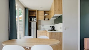 Une cuisine compacte avec une table et des chaises en bois, un four à micro-ondes encastré et un réfrigérateur.
