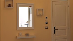 A bathroom with a white door, a mirror, and a shelf with a vase and a bowl. - Arco Suite (Lecce)