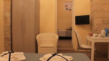 Ein Hotelzimmer mit Bett, Schrank, Fernseher, Tisch mit Vase und Stuhl.