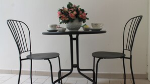 A small table with a vase of flowers, two chairs, and two teacups on either side. - Arco Suite (Lecce)
