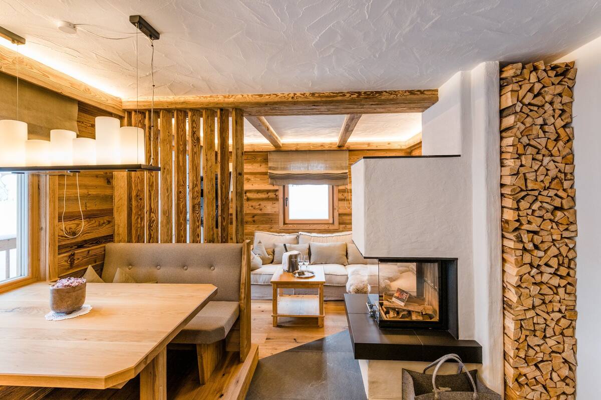 Ein gemütliches Blockhaus-Interieur mit einem Holztisch, bequemen Sitzgelegenheiten, einem Kamin und einer Holzwand.