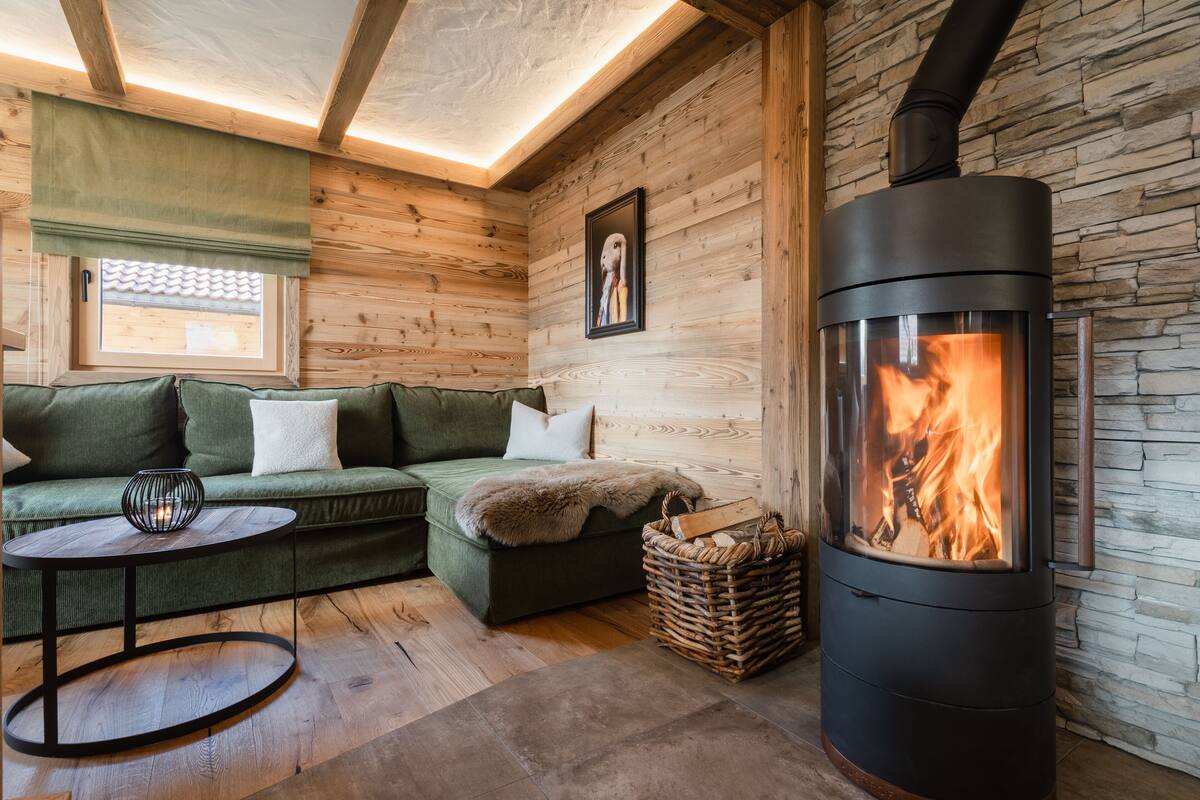 Ein gemütliches Zimmer mit Holzvertäfelung, einer Couch, einem kleinen Tisch und einem Kaminofen.