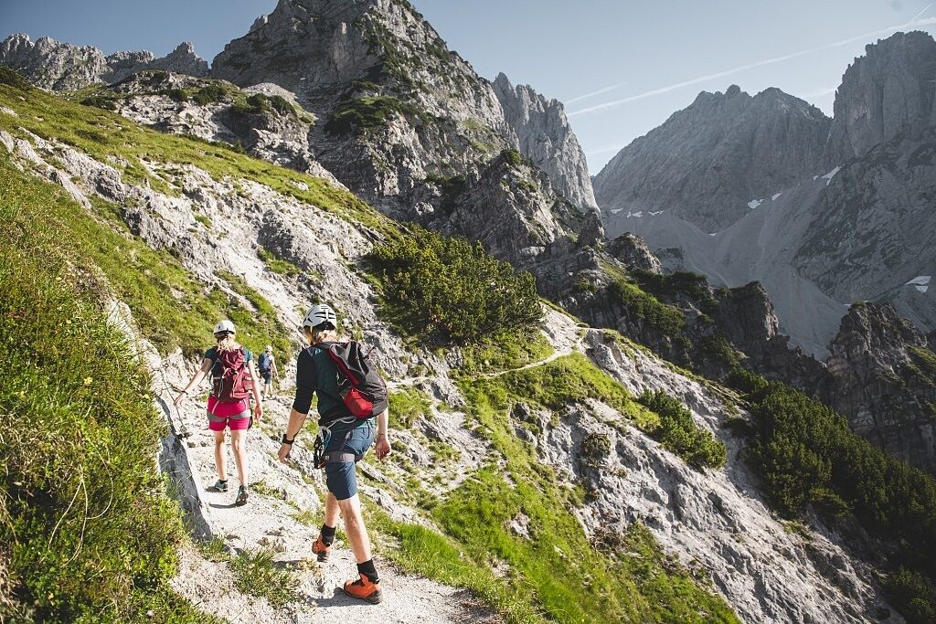 A mountainous hiking trail with rocky terrain and sparse vegetation.