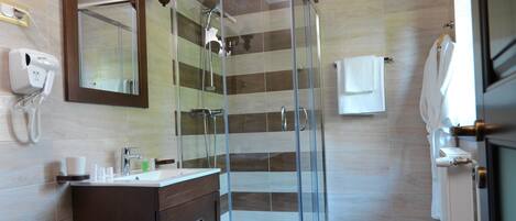 Un baño moderno con ducha de vidrio, tocador con espejo y barra para toallas.