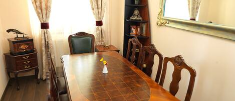 Comedor con mesa de madera, sillas, aparador y espejo en la pared.
