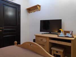 Una habitación con escritorio de madera, televisor, mueble pequeño y cama.