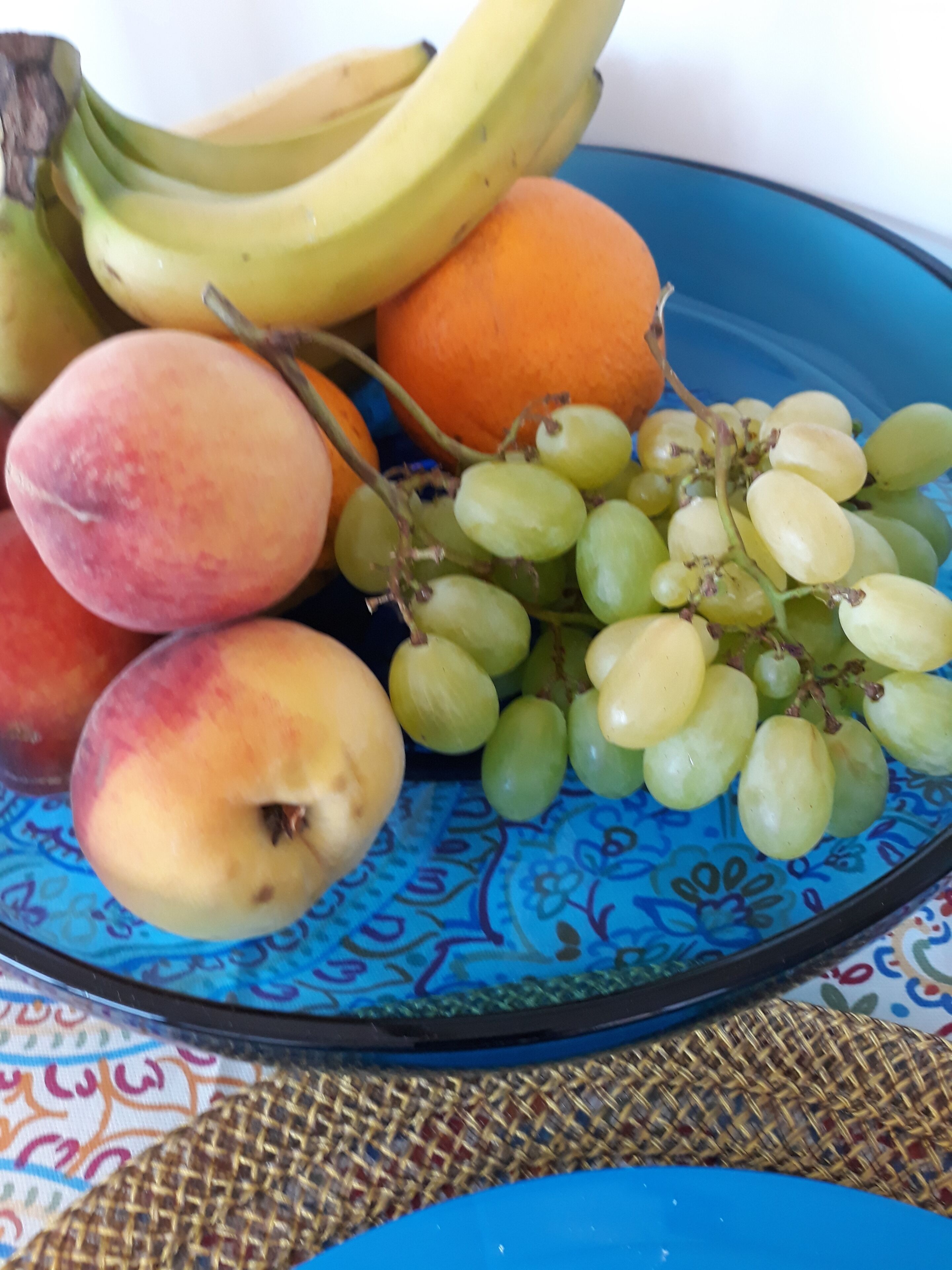 A plate with peaches, grapes, and bananas.