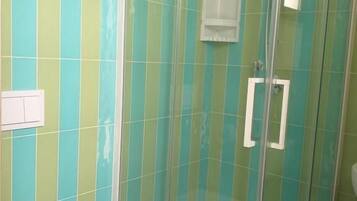 A bathroom with a glass-enclosed shower, a white toilet, and a tiled wall with a striped pattern.